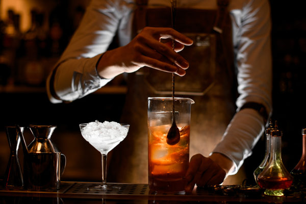 bartender stirs alcoholic cocktail on bar
